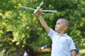 Boy outside holding up toy airplane