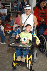 Lady pushing stroller with small boy with disabilities